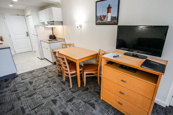 Photo of kitchen, and living area with table and chairs, and television on TV stand.
